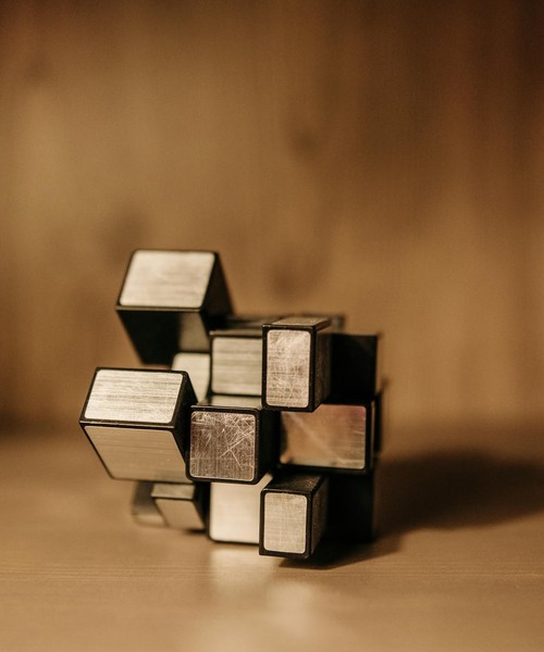 Close-up of a metal puzzle cube against a warm blurred background.